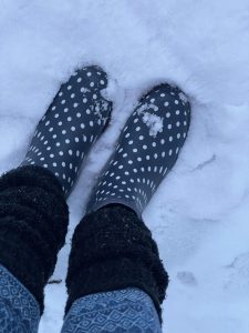 Gemütliche Gummistiefel mit weißen Punkten auf Schnee, geeignet für winterliche Spaziergänge und Naturerkundungen.