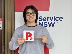 Successful driving student celebrating passing their practical driving test at the registry.