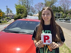 Happy student holding new P-plates after passing their practical exam.