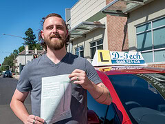 Happy student holding new P-plates after passing their practical exam.