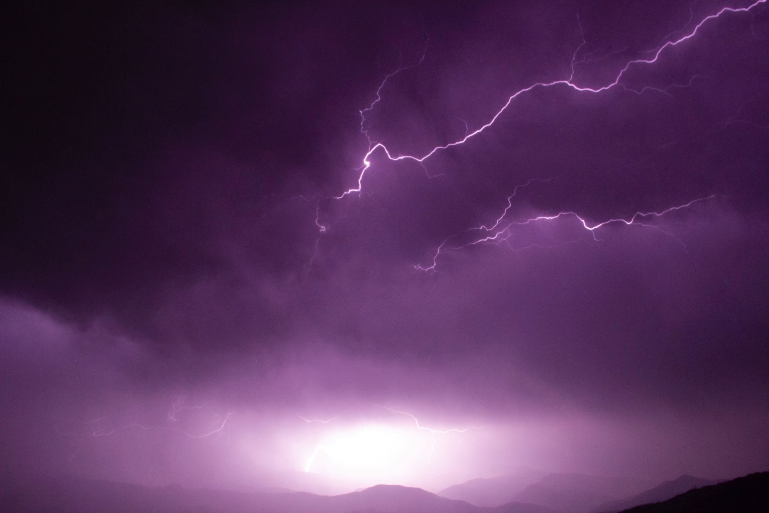 purple storm clouds and lightning over mountains