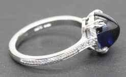 Silver ring featuring a large, deep blue gemstone and intricate engraved band design.