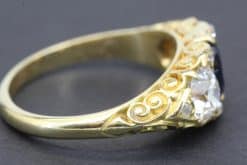 Gold ring with detailed scrollwork and a sparkling central diamond.