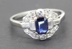 Elegant sapphire and diamond ring with a central blue gemstone surrounded by sparkling diamonds.