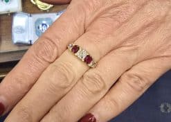 Elegant gold ring with three rubies and diamonds, perfect for special occasions.