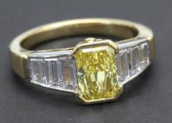 Stunning yellow diamond engagement ring with baguette-cut diamonds in gold setting.