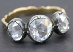 Diamond ring with three large, clear gemstones and a gold band.