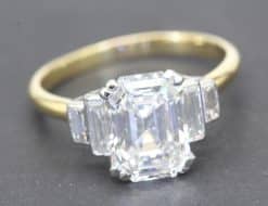 Elegant emerald cut diamond engagement ring with gold band.