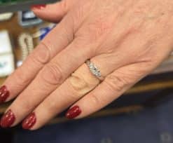 Diamond engagement ring on woman's finger, showcasing fine jewelry craftsmanship.