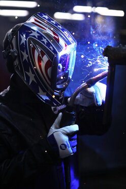 Closeup from the side of welder welding out of position