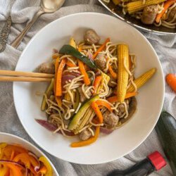 sausage stir fry in a bowl with baby corn and noodles.