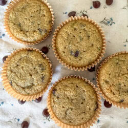 Close-up of healthy zucchini muffins with chocolate chips scattered on a floral kitchen towel