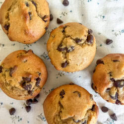 Einkorn flour sour cream chocolate chip muffins arranged sideways on a neutral floral background