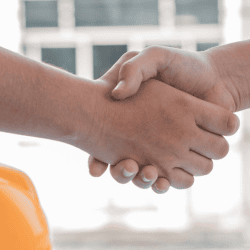 Image of two workers shaking hands on a construction site.