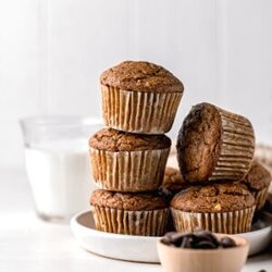 stack of pumpkin banana muffins on a white plate with a glass of dairy free milk