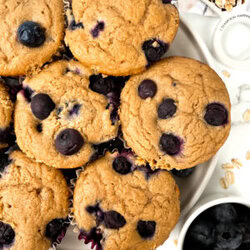 oat flour blueberry muffins on a plate next to oats and berries