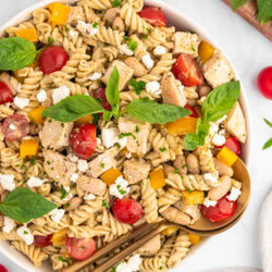 Serving spoons in a bowl of High Protein Pasta Salad.
