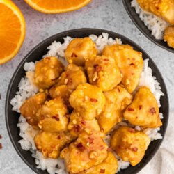 air fryer orange chicken in a black bowl with rice next to an orange