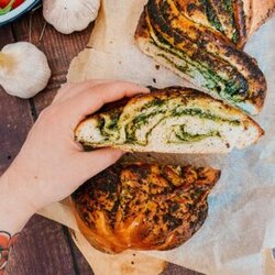 close up of garlic loaf, garlic bread on, garlic and tomatoes on the side, on a wooden background