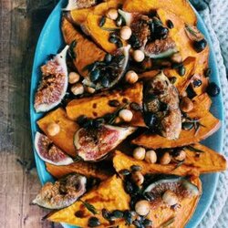 sweet potatoes, figs, hazelnuts and pumpkin seeds on a plate, a napkin under it