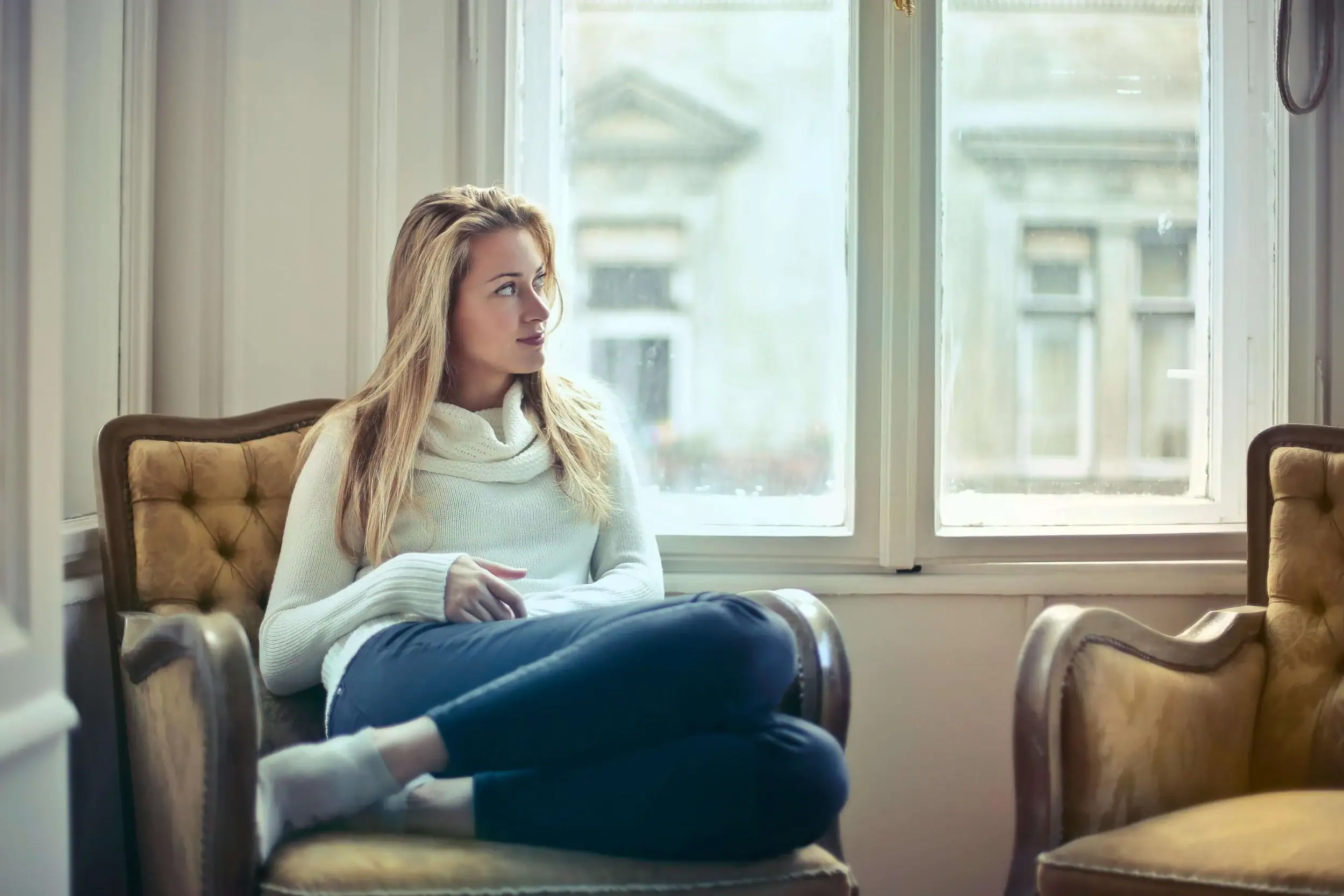 Woman sitting on a couch in contemplation. Begin somatic therapy online in Ann Arbor and Detroit, Michigan