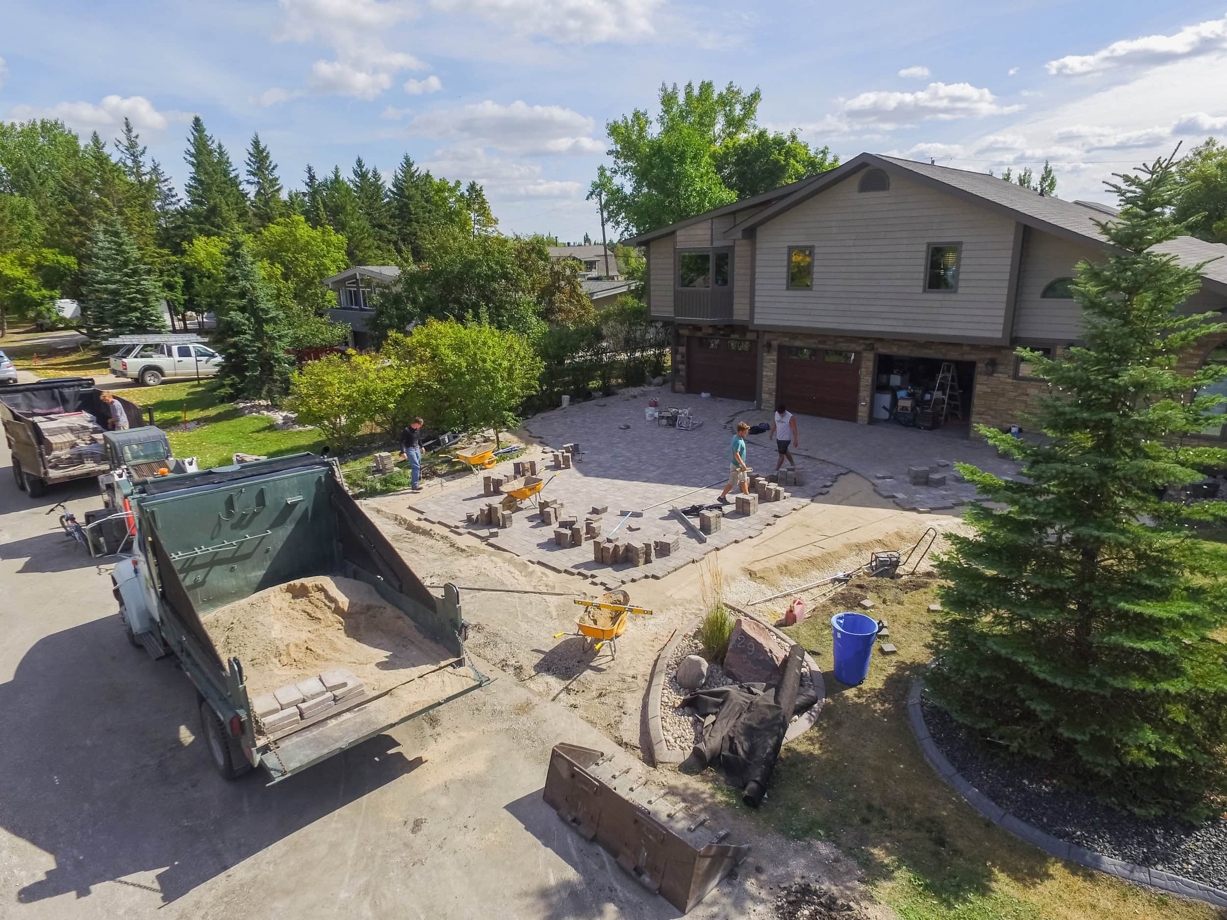 Ongoing residential landscaping construction with stone patio installation and outdoor living space design.