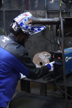 Image of welder from behind adjusting settings on a Miller power source