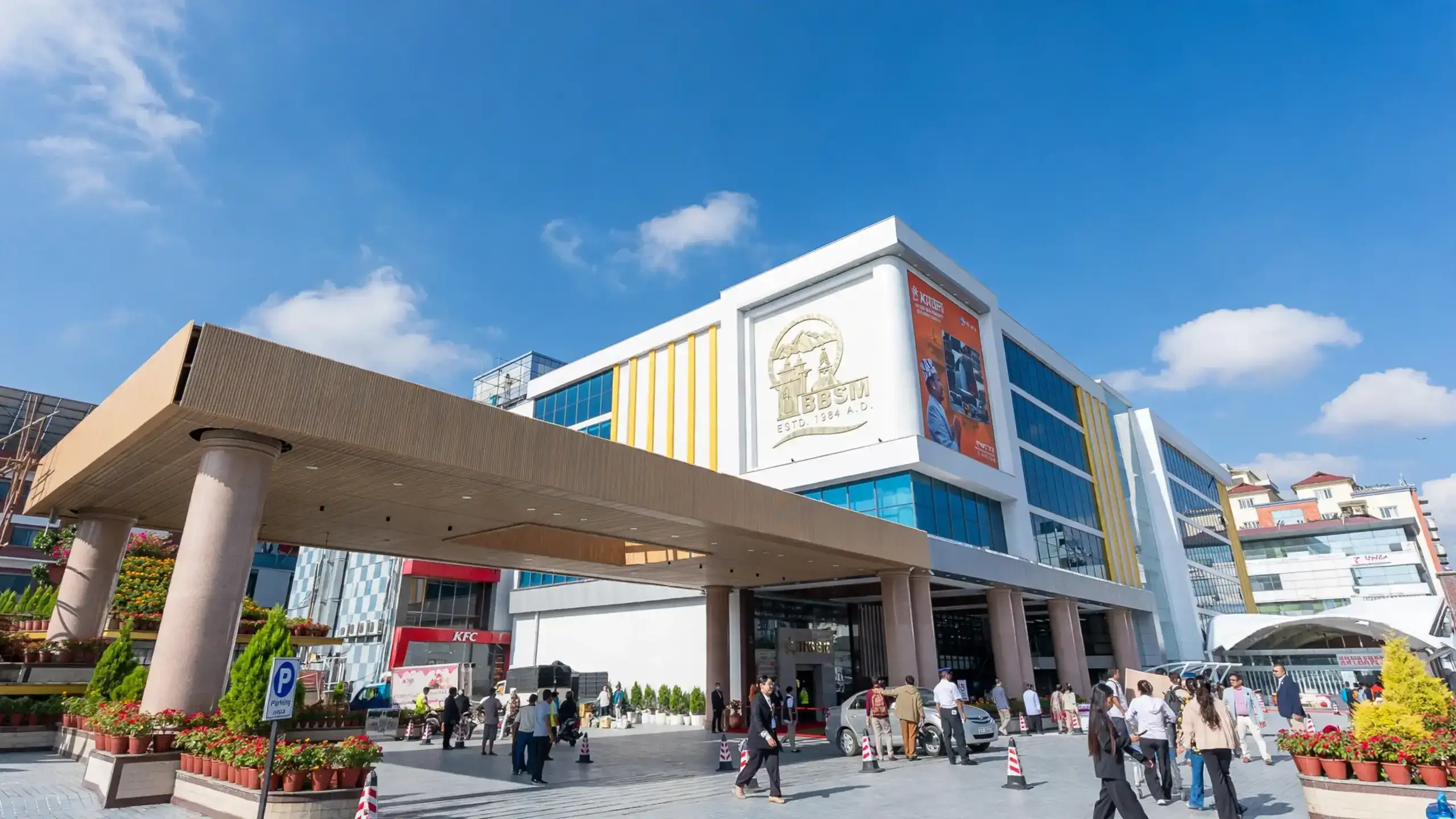 Exterior view of BBSM (Bhat-Bhateni Super Market) with visitors gathered at the main entrance on a clear day.