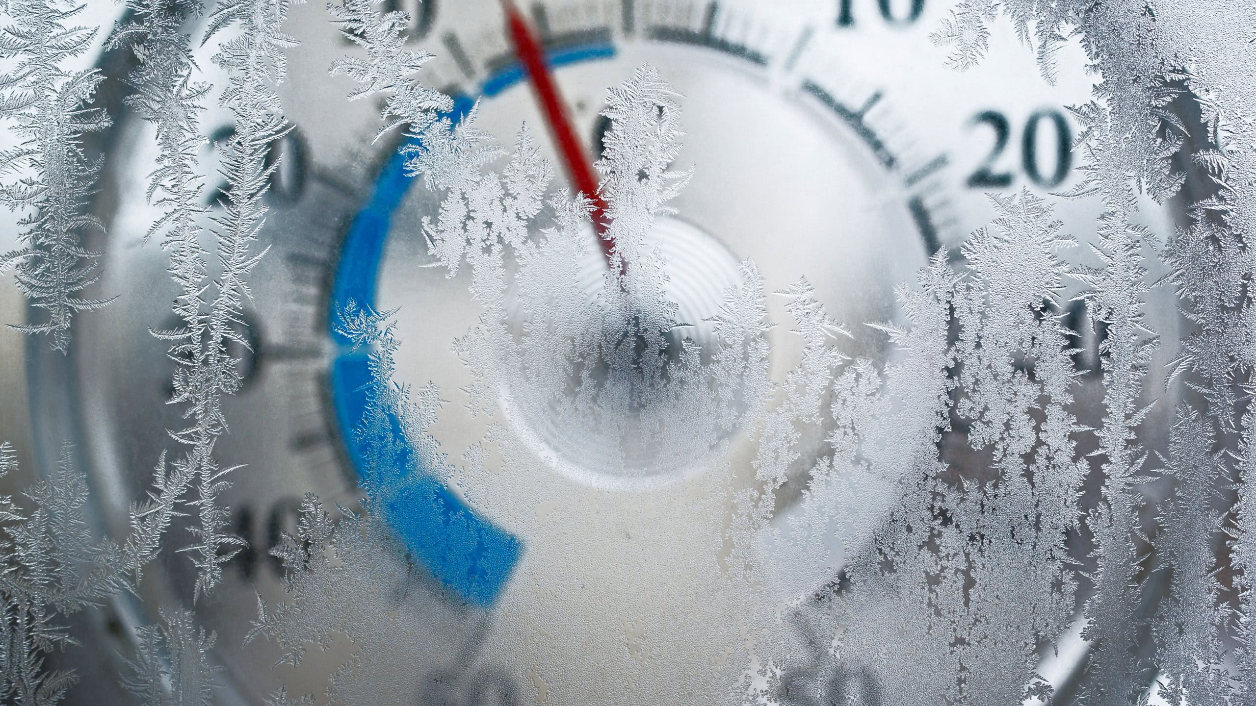 En närbild av en termometer delvis täckt av frost. Röda och blå markeringar syns på termometern.