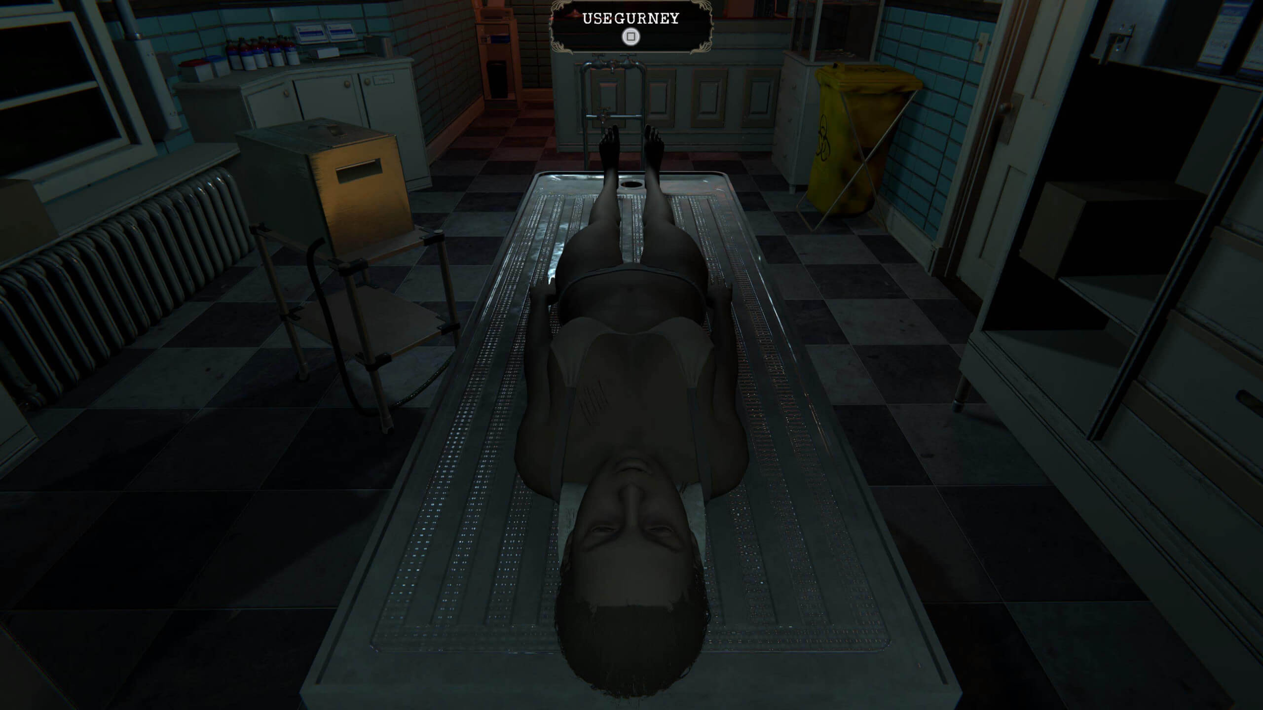 Screenshot from Mortuary Assistant. In the centre of the screen is a gurney with a body on it. At the top of the screen it says square to use gurney. To the left is a pump that the player has to use. The gurney has came to a stop in front of a drain.