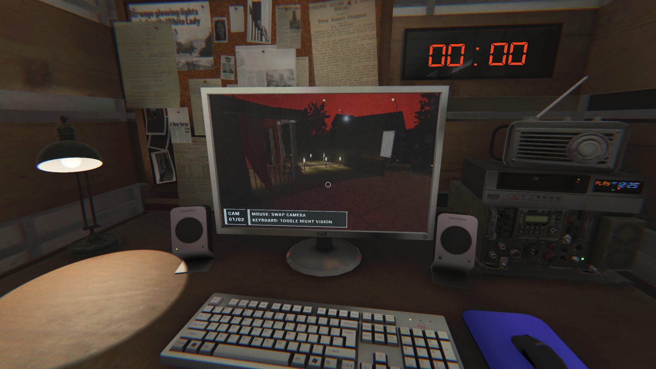 A cluttered desktop showing a computer monitor displaying security cam footage, surrounded by notes and old electronics.