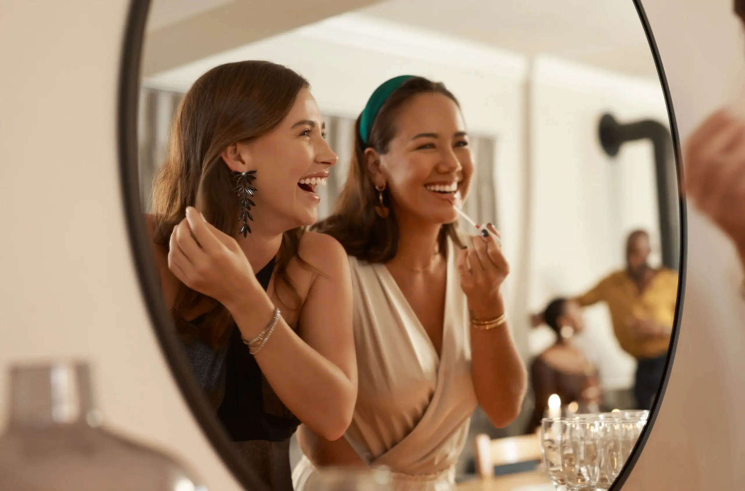 Two residents smiling together while getting ready for a community social gathering inside a luxury apartment clubhouse.