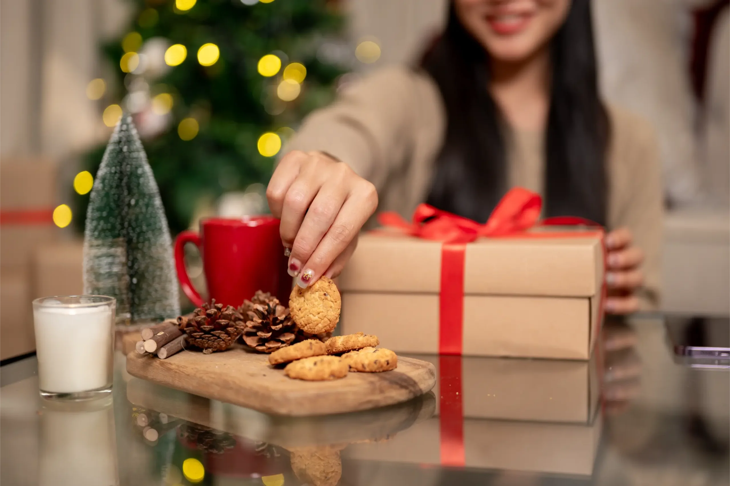 Woman grabbing a cookie with presents and Christmas tree