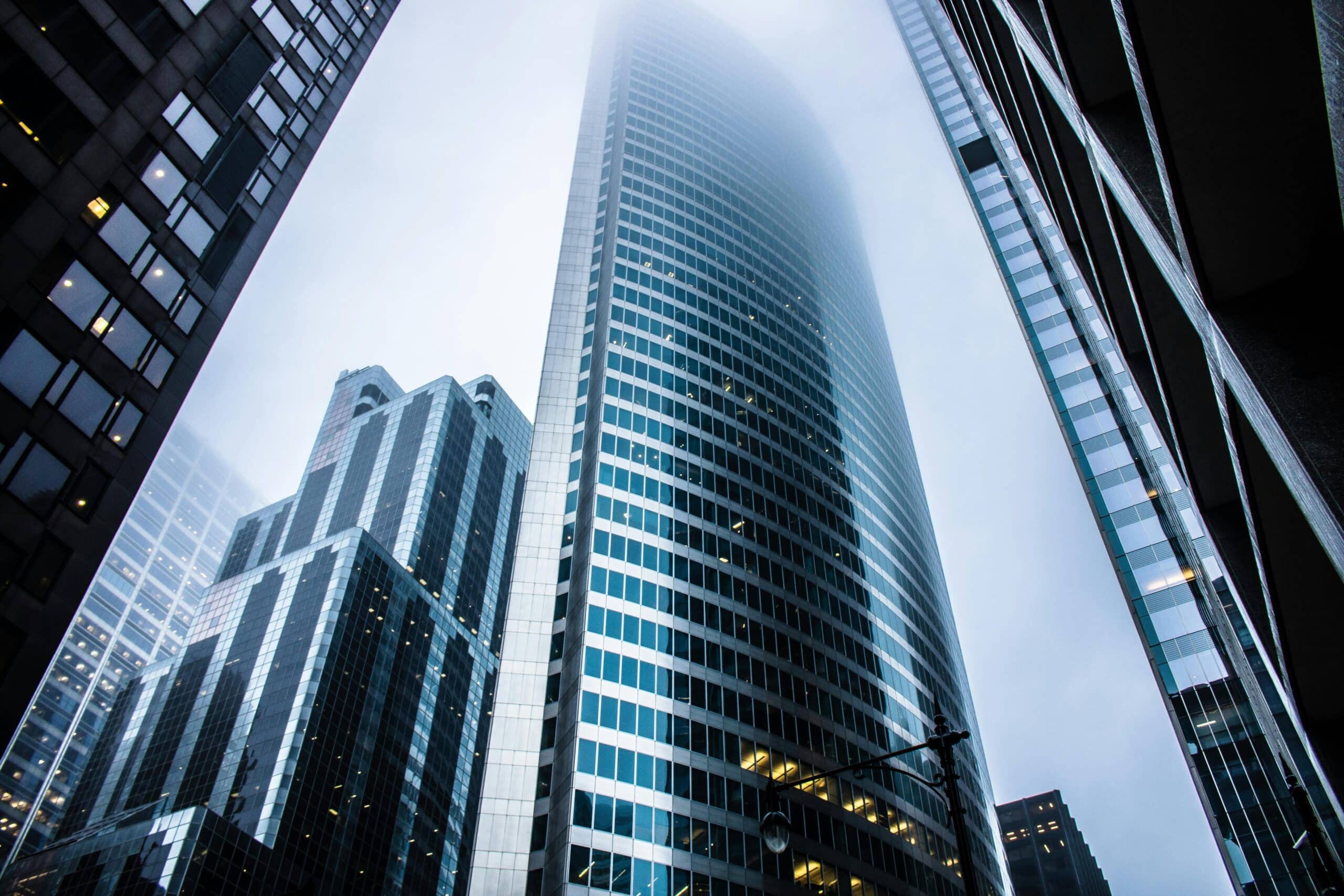 Tall glass building surrounded by others just like it.