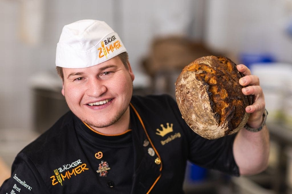 Frischer Sauerteigbrot, Bäcker zeigt das fertige, rustikale Brot in der Backstube. Hochwertige Backk.