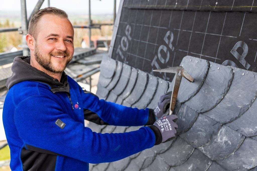 Dachdecker bei Arbeit an einem Dach mit Schieferziegeln, professionelles Handwerk.