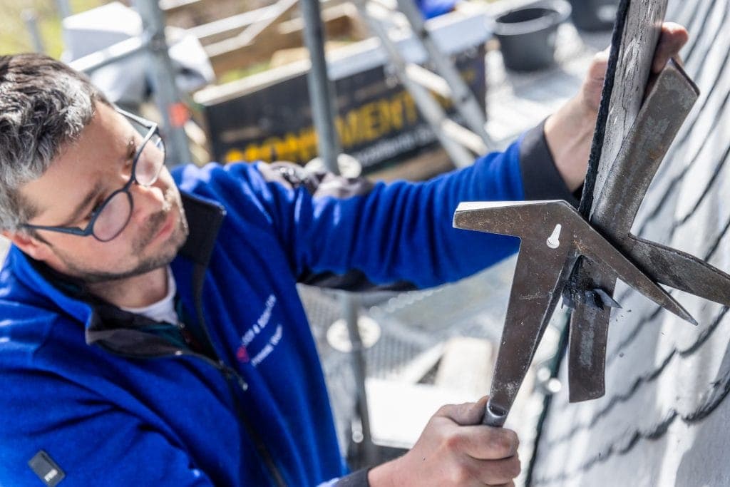 Mann bei Bauarbeiten mit Hammer und Werkzeug an einer Wand.