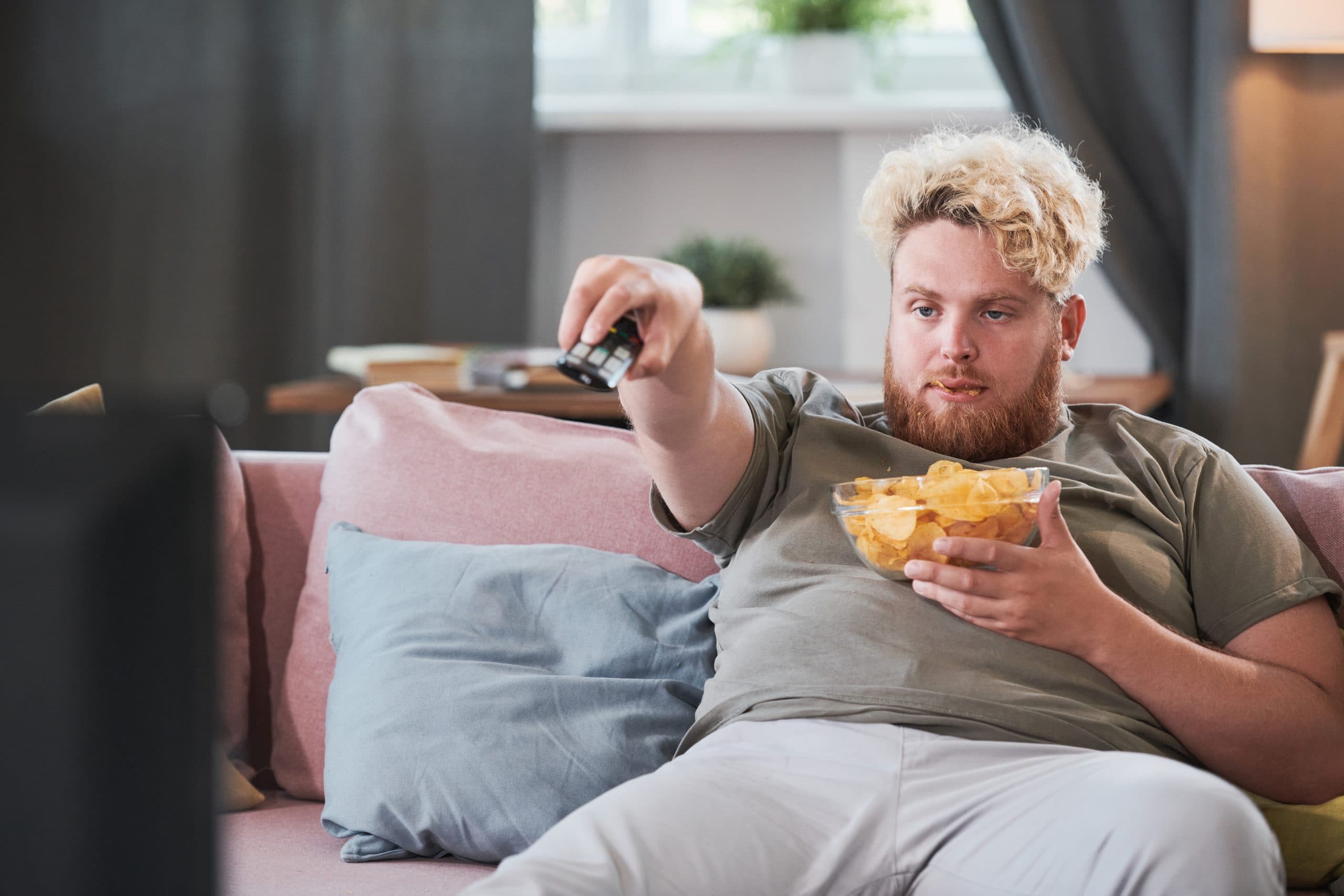 Overweight man watching TV at home