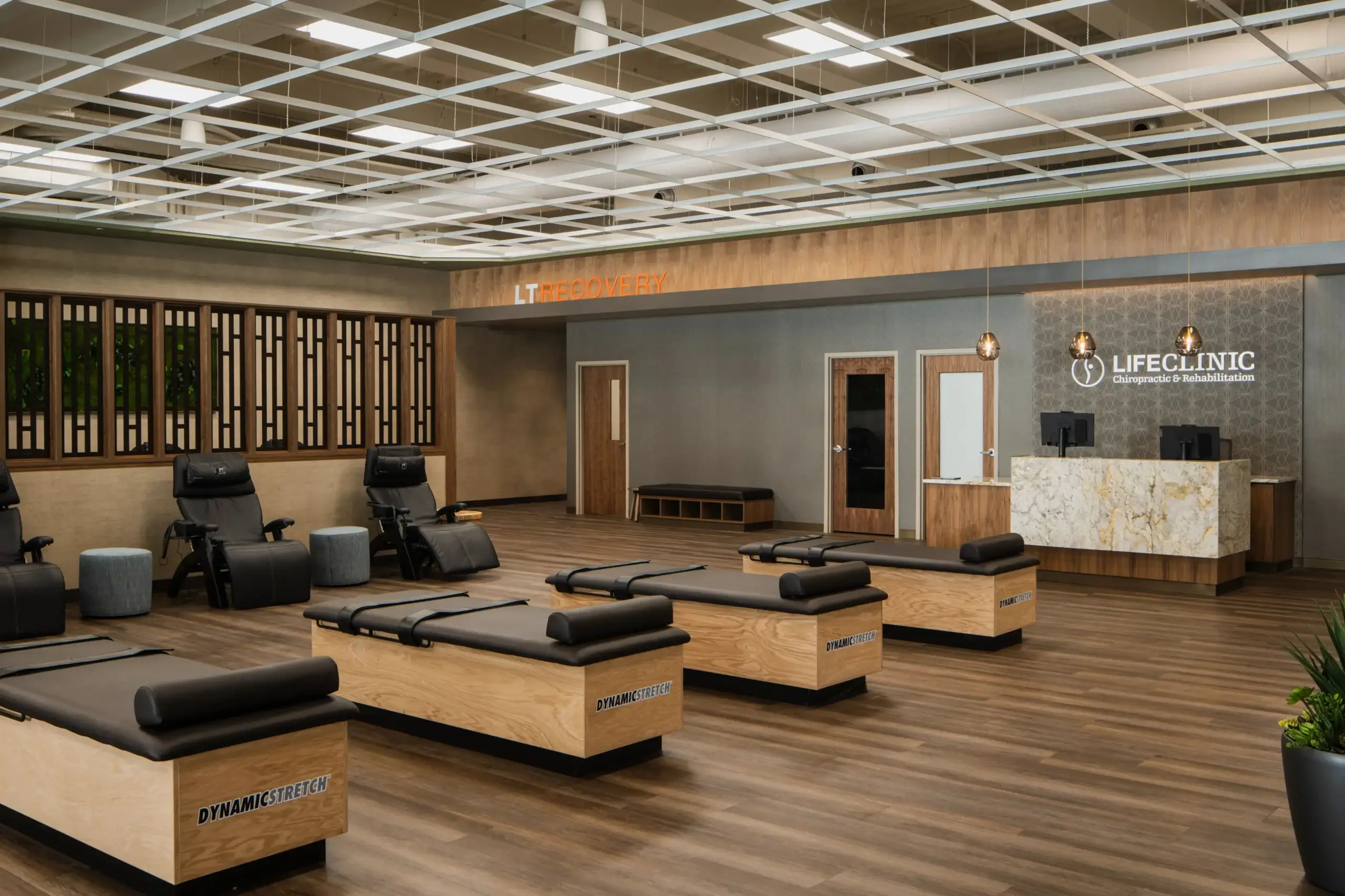 Modern wellness and recovery center with Dynamic Stretch therapy tables, recovery chairs, chiropractic services, and a welcoming reception area.
