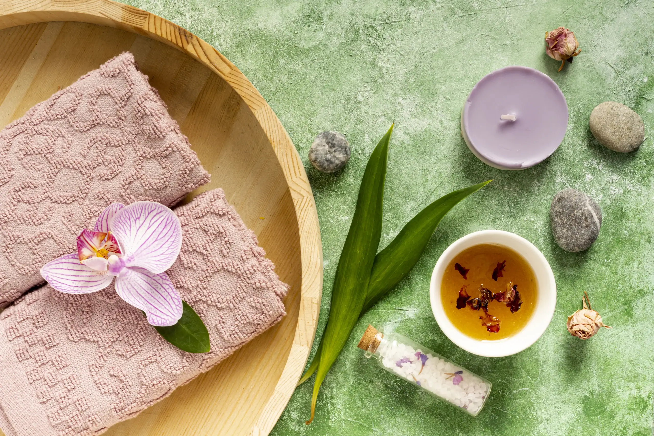 Ayurvedic Summer Treatments spa setup with herbal oil, orchid flower, towels, candle, bath salts, and natural wellness elements arranged for a calming and rejuvenating summer therapy experience.