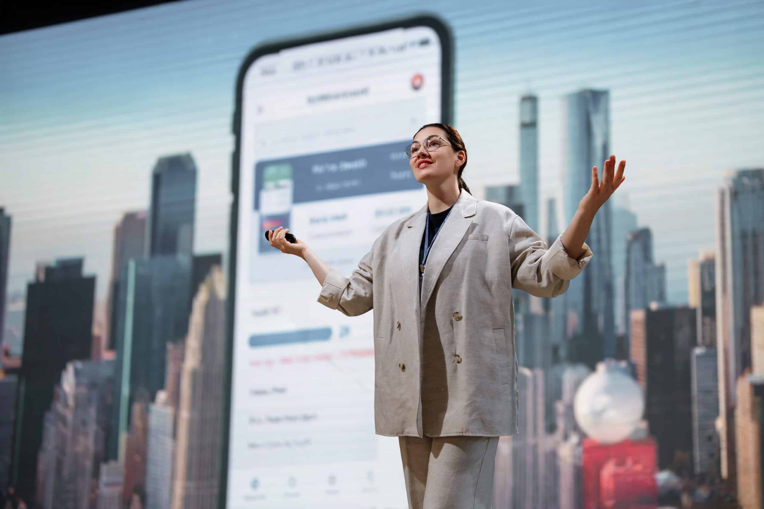 Woman presenting mobile app and ai on screen, cityscape backdrop. Business presentation.