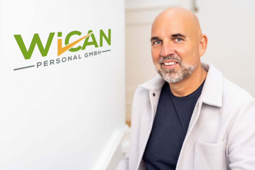 Portrait eines Mannes mit Bart vor WICAN Personal GmbH Logo.