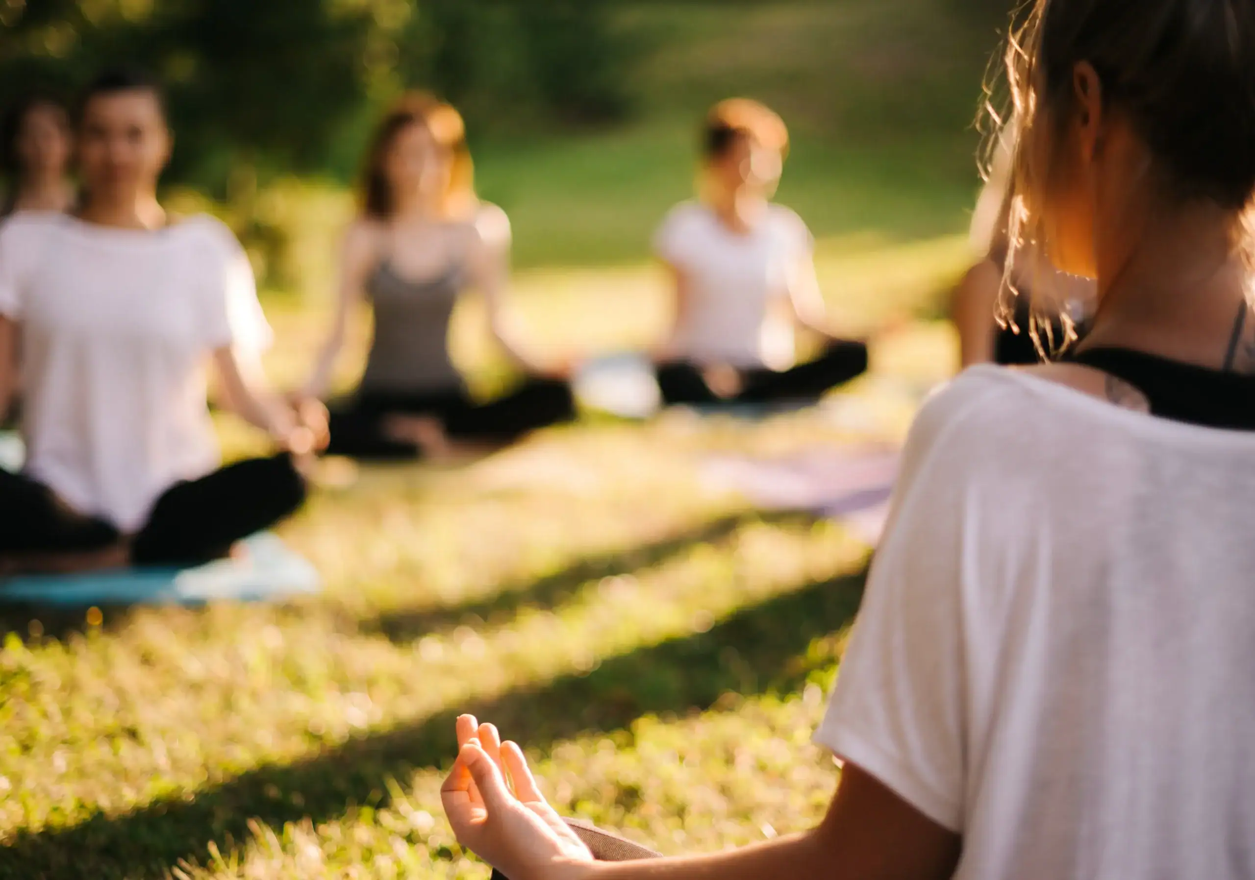 Residents participating in a peaceful outdoor yoga session on a landscaped community lawn during golden hour.