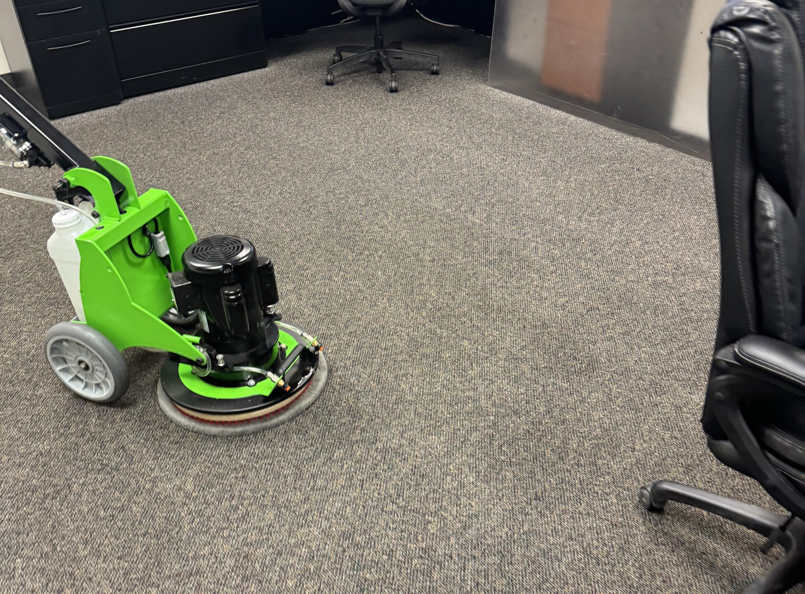 Low moisture carpet cleaning machine cleaning a commercial carpet. Trinity Phoenix orbital machine