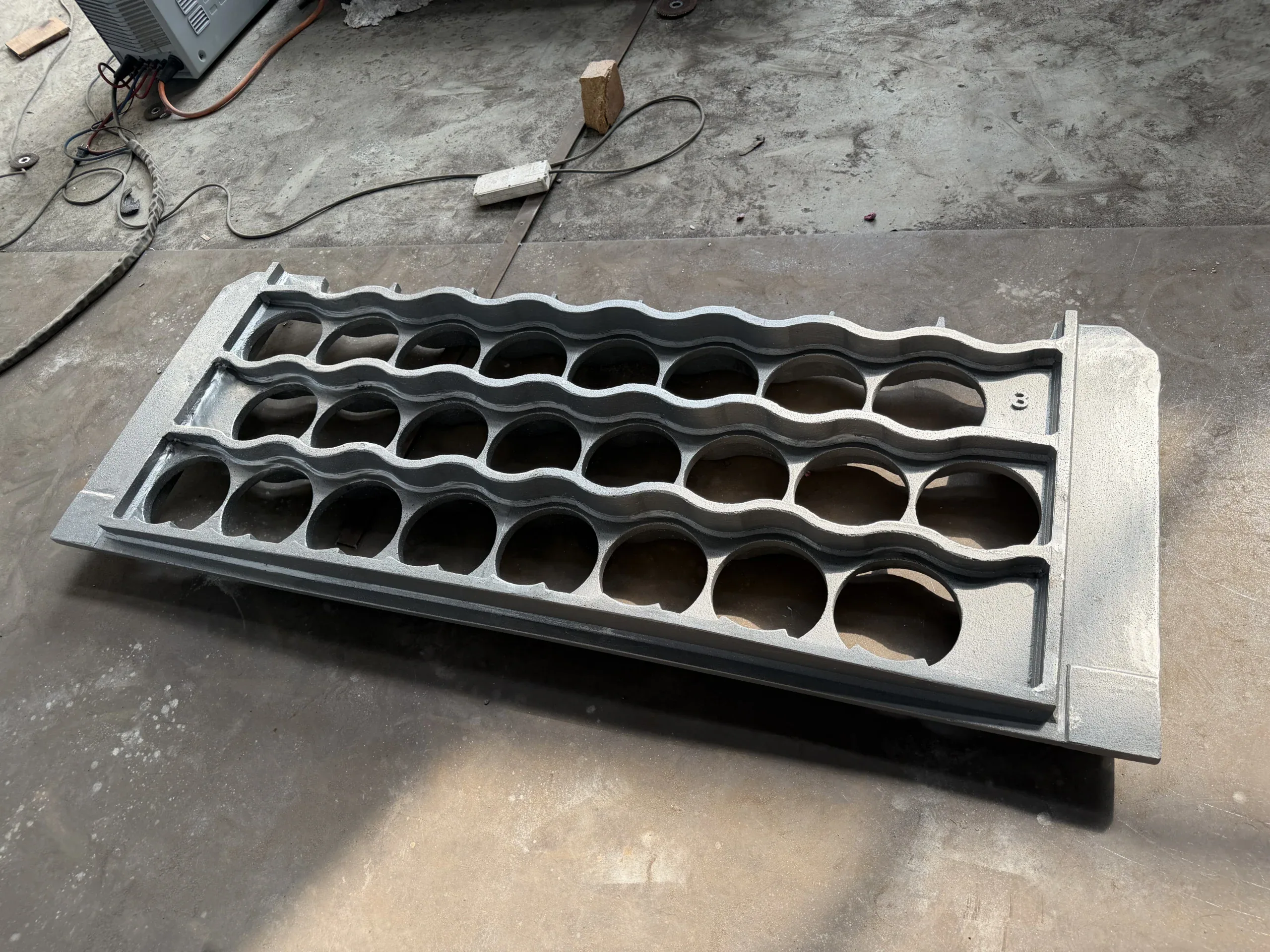 Rectangular furnace tray with elongated open-grid cells lying in the workshop