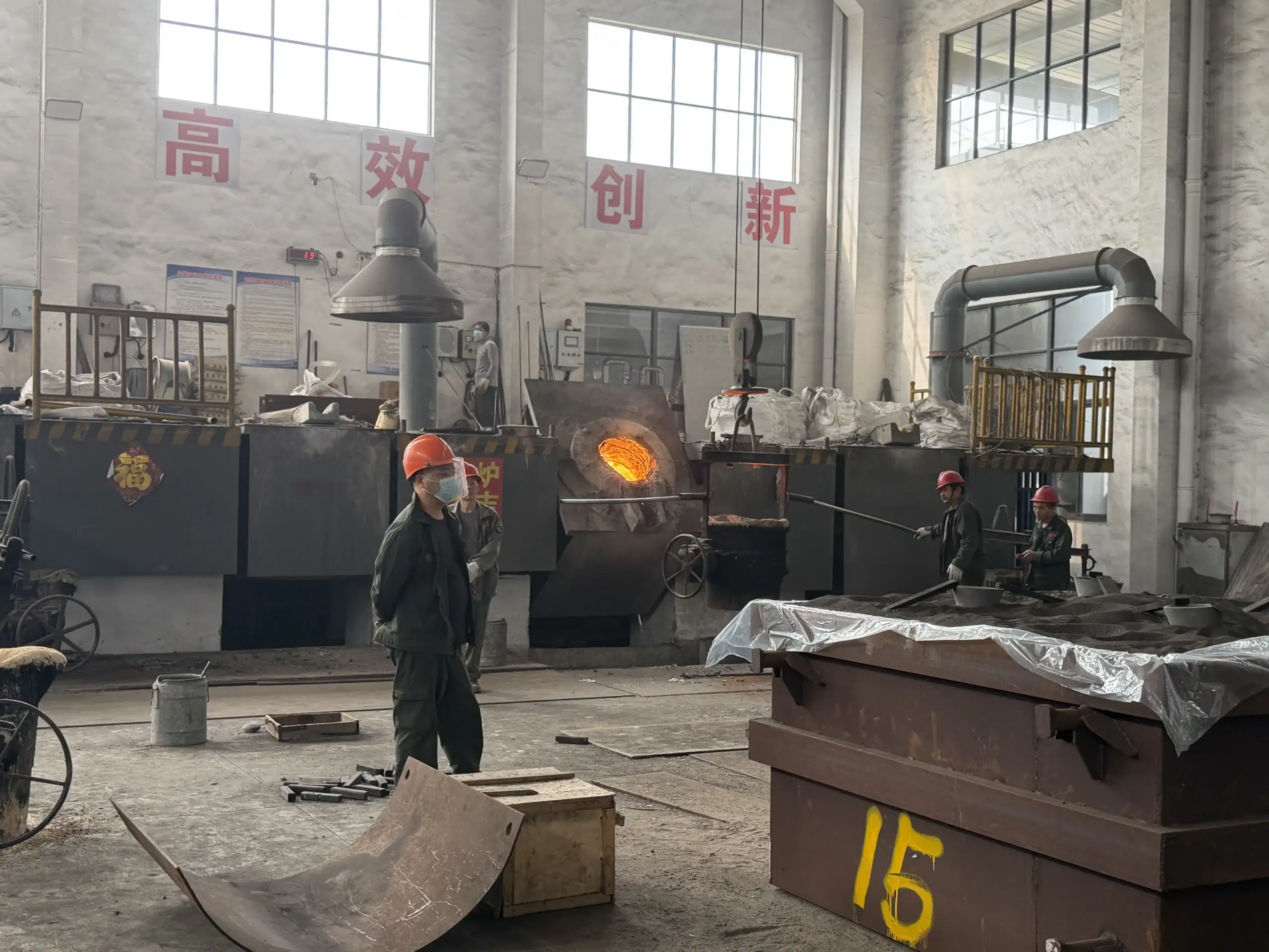 Workers beside an operating melting furnace and mould boxes in the ECOOSUN foundry