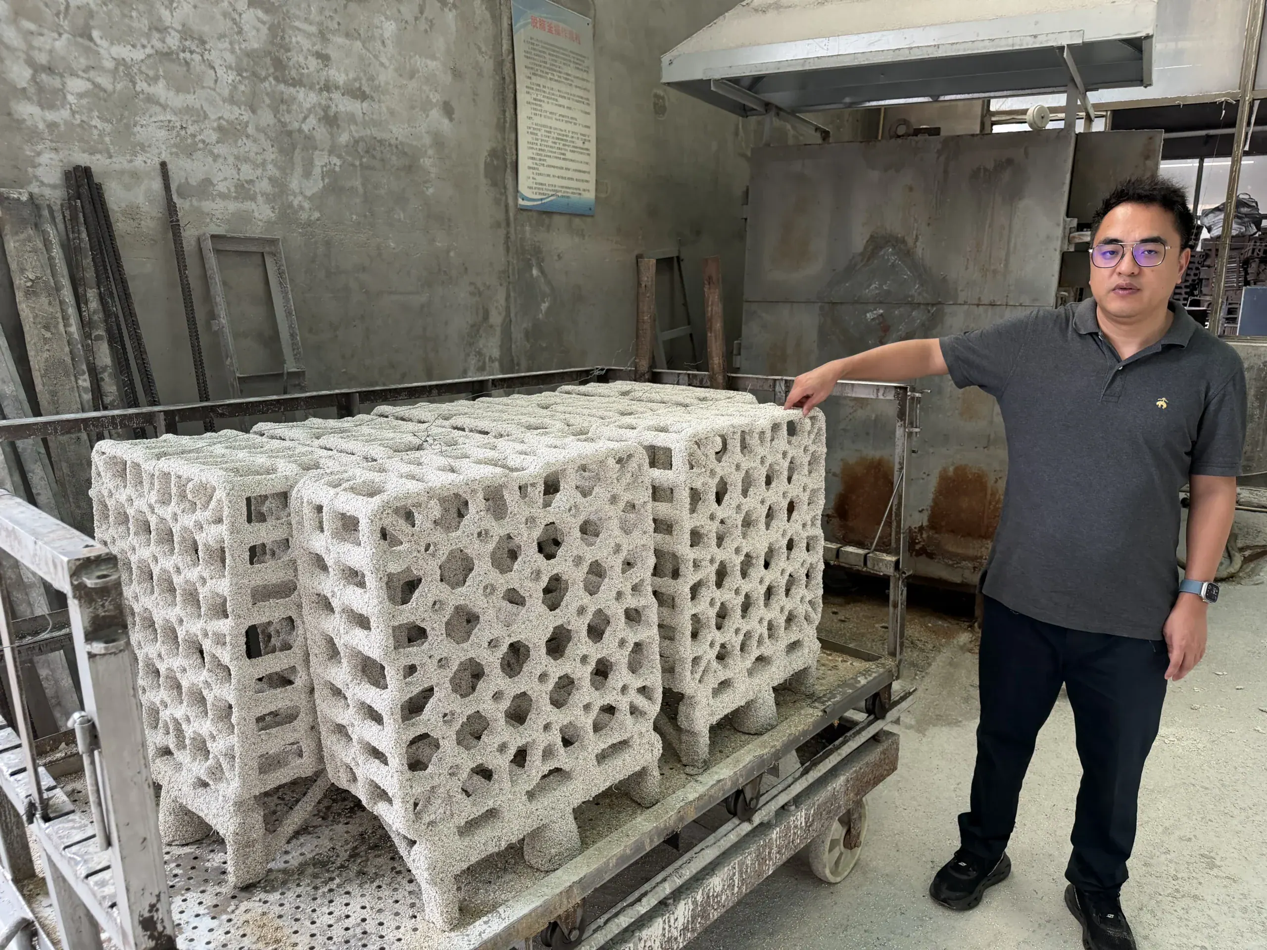 White honeycomb casting patterns on a cart beside a worker in the workshop
