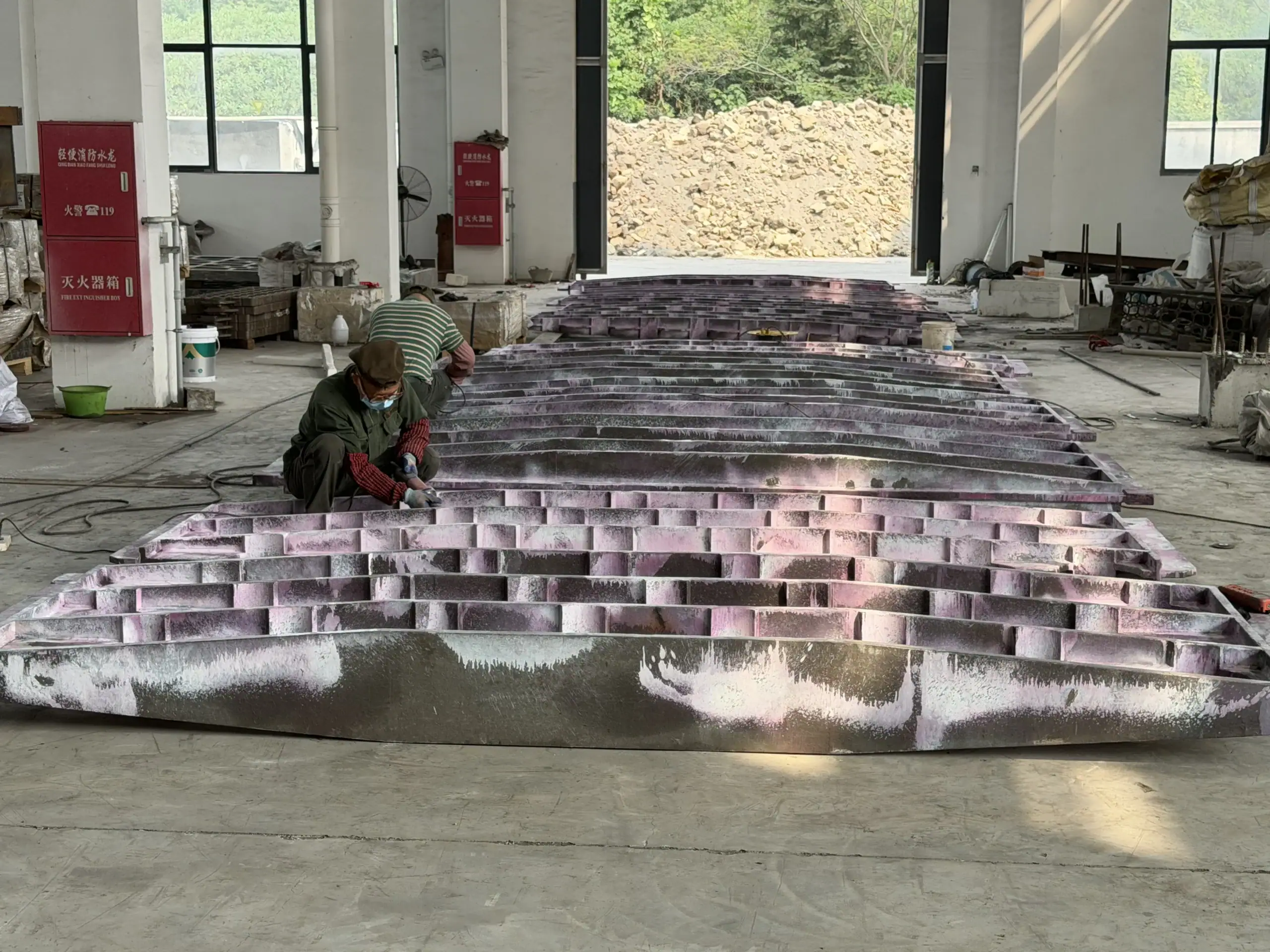 Rows of cast furnace components on the floor beside a worker in the production workshop