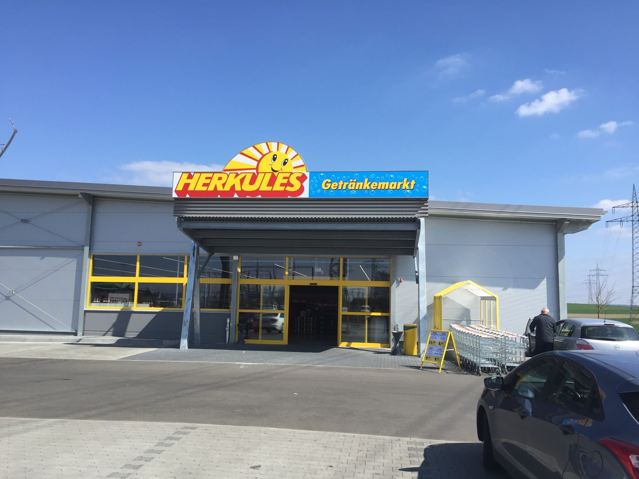 Ein robustes Vordach aus Wellblech von Stahl- und Metallbau Drost über dem Haupteingang des Herkules Getränkemarktes, bei klarem blauem Himmel.