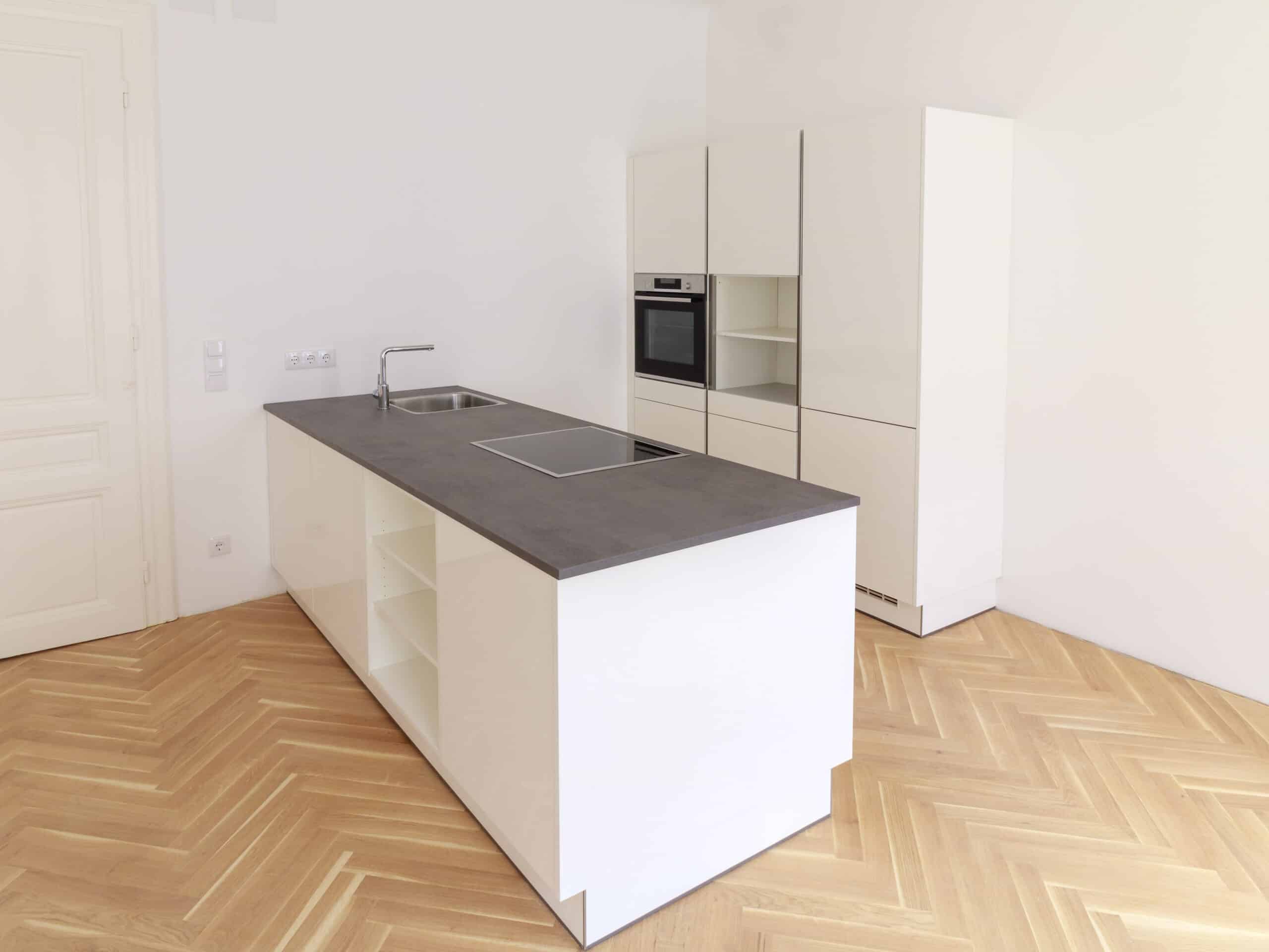 Küchenmontage - Modern eingerichtete weiße Küche mit Kochinsel und eingebauten Elektrogeräten nach professioneller Küchenmontage